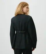 Blazer de sastrería negro de corte entallado, sin cuello, con escote en V profundo, manga larga y cierre frontal de un botón. Cuenta con bolsillos frontales con tapa, recortes estructurados y tira trasera con hebilla.