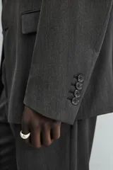 Blazer de corte regular fit en color gris oscuro, confeccionada en tejido con viscosa. Presenta cuello con solapas de muesca, cierre frontal con dos botones, bolsillos laterales con solapa y aberturas en la espalda.