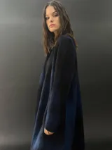 Tapado largo gris de lana merino con bolsillos laterales y corte particular en los hombros.