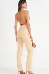 Pantalón de jean color beige con apliques de strass dorados.