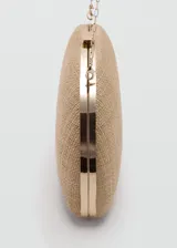 Bolso tipo clutch de diseño ovalado y rígido, revestido en rafia color tostado, con cierre metálico a presión en la parte superior y detalles metálicos.