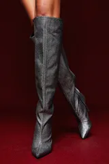 Bota alta plateada con textura brillante, punta fina y taco aguja.