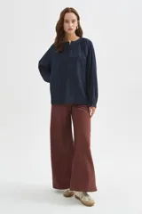 Blusa azul marino de viscosa, con cuello mao, escote con botones y frunces. Presenta mangas largas holgadas y detalles bordados al tono en el frente.