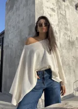 Poncho de hilo liviano en color crudo, con diseño sin cuello y caída fluida, ideal para media estación.