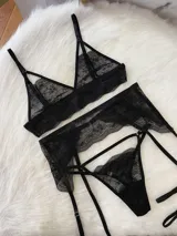 Conjunto de lencería de encaje negro compuesto por un bralette triangular, una tanga y un portaligas integrado. El diseño presenta detalles de encaje floral, breteles regulables y tiras elásticas ajustables.