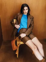 Bermuda marrón de cuero sintético, tiro alto, con bolsillos laterales y cierre frontal con botón y cremallera.