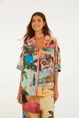 Camisa de viscosa con estampado ilustrado de escenas de Río de Janeiro, que incluye playa, morros y elementos tropicales. Cuenta con cuello camisero, botones frontales y mangas cortas holgadas.