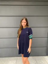 Vestido corto azul marino de hilo, con cuello redondo y mangas cortas con rayas verdes y blancas.