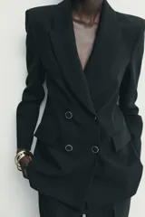 Blazer de corte estructurado con hombreras, cuello solapa y manga larga. Presenta un diseño cruzado con cierre frontal de botones y bolsillos delanteros con solapa.