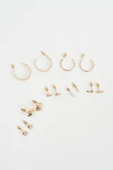 Set de caravanas compuesto por múltiples pares de aros en tono dorado, incluyendo aros tipo argolla de diferentes tamaños, aros con perlas pequeñas, aros con formas geométricas y aros con cristales engarzados.