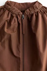 Campera bomber oversized color marrón con cuello elevado fruncido, cierre frontal y mangas raglán con puños elásticos.