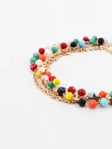 Set de cuatro pulseras doradas, compuestas por cadenas finas decoradas con cuentas de colores facetadas y pequeños dijes en forma de estrella.