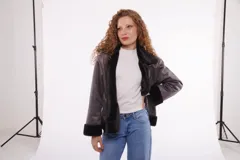 Campera gris oscuro con cuello alto con solapa y cierre con hebillas.