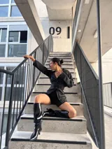 Blazer negro a rayas verticales blancas, con solapas de muesca, cierre cruzado con botones y corte entallado.