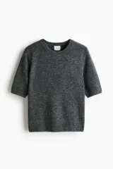 Remera corta de punto suave color gris melange, con cuello redondo y mangas cortas, terminaciones en punto acanalado.