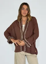 Saco color crudo de tejido de punto con detalle de volados en el frente y en los puños.