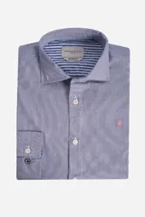 Camisa de manga larga con diseño de rayas verticales finas en tono azul y blanco. Presenta cuello clásico, cierre frontal con botones y logo bordado en color rosado en el pecho. El interior del cuello y los puños cuentan con un detalle de rayas horizontales en contraste.