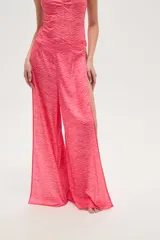 Pantalon de tiro bajo con diseño de aberturas laterales pronunciadas, unidas por argollas metálicas. Presenta un estampado animal print tipo cebra en tonos fucsia y rosado, con corte amplio y fluido.