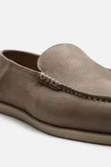 Mocasín casual de piel con acabado nobuck, color marrón claro. Presenta un corte liso con detalle de bordón y horma redonda. La suela es plana y a tono con el calzado.