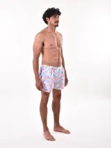 Short de baño blanco con estampado de hojas en tonos azules y rosados, cintura elástica con cordón ajustable.