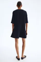 Vestido corto azul marino con finas rayas verticales blancas. Presenta cuello redondo, cierre oculto en la espalda, mangas al codo y una falda con corte circular que genera un efecto volante en el ruedo.