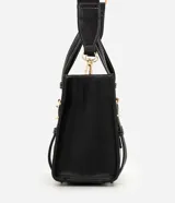 Cartera satchel mediana de color marrón, confeccionada en poliuretano con diseño estructurado, costuras en contraste y herrajes metálicos dorados. Cuenta con doble asa de mano, correas decorativas verticales con hebillas en la parte frontal y una correa larga ajustable y desmontable para llevar al hombro o cruzada.