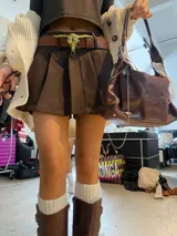 Cinturón marrón de cuero sintético con hebilla dorada en forma de cráneo de toro.