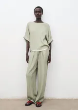 Pantalón largo de tiro alto color verde, con cintura elástica y cordón ajustable, de diseño recto y tejido con textura.