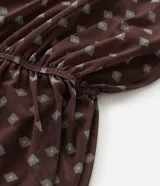 Blusa tipo bata confeccionada en tule con forro interior, escote en V, mangas cortas con detalle de lazo y cintura fruncida. Presenta un estampado geométrico tipo pañuelo.