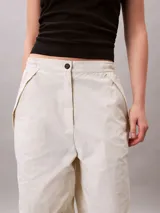 Pantalón parachute de nailon color crudo, de corte holgado, cintura elástica con cordón interior, puños con cordón y cremallera, cierre mediante botón y cremallera, diseño de bolsillo superpuesto y bordado de Calvin Klein en la cadera.