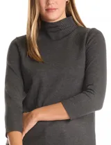 Buzo de tejido fino en color gris oscuro, con cuello alto acanalado y mangas tres cuartos. Presenta un diseño con líneas acanaladas en diagonal desde el cuello hacia las sisas y pequeños tajos laterales en el ruedo.