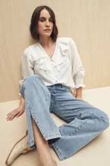 Jean de corte recto confeccionado en denim con spandex, de tiro medio y color azul claro. Presenta un tajo lateral en el ruedo de ambas piernas.