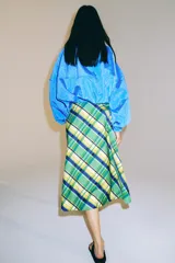 Falda midi de tiro medio marca ZWE Collection, confeccionada en hilatura de algodón con diseño de cuadros tipo tartán en tonos verdes, azules y amarillos. Tiene corte evasé y cierre lateral con cremallera oculta.