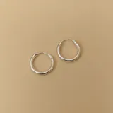 Par de aros tipo argolla de plata 925, de tamaño mediano y forma tubular.