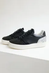 Zapatillas urbanas de cuero negro con cordones negros y suela blanca.
