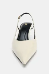 Zapato de tacón destalonado con tira trasera ajustable mediante hebilla metálica. Presenta un diseño de punta fina, escote redondo y tacón fino de altura media.