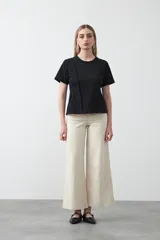 Remera de manga corta y cuello redondo, confeccionada en algodón. Presenta costuras verticales visibles en el frente que generan un efecto de entalle y estructura en la cintura.