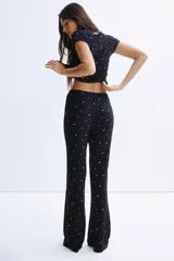 Pijama de dos piezas confeccionado en punto acanalado de modal. Incluye una remera de cuello redondo con mangas cortas terminadas en ribete de encaje y un pantalón con cintura elástica y corte levemente acampanado.