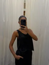 Musculosa negra con acabado satinado y sutil brillo, de corte holgado y diseño básico con breteles anchos.