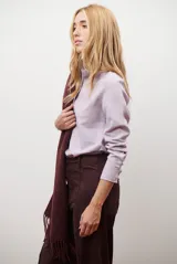 Camisa blanca de manga larga con cuello clásico y botones frontales. Tiene un bolsillo en el pecho con un pequeño logo bordado.