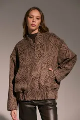 Campera tipo bomber de corte holgado con diseño estampado de cebra en tonos marrones. Presenta cuello redondo, cierre frontal con botones a presión y mangas largas amplias.