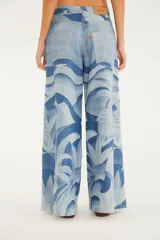 Pantalón palazzo de denim con tiro alto, piernas amplias y estampado tropical en tonos azules.