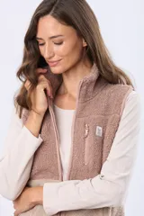 Chaleco de sherpa combinado en tonos beige, con cuello alto y cierre frontal. Presenta una textura suave y abrigada, ideal para capas adicionales.