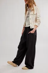 Pantalon de lino y algodon color beige, de tiro bajo, estilo relajado con cintura elastizada ajustable mediante cordón y bolsillos laterales.