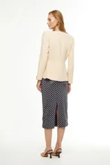 Blazer color arena con escote en V, corte entallado y mangas largas.