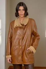 Campera de cuero negro con diseño de paneles, cuello alto y puños con forro de corderito sintético negro. Presenta cierre frontal con botones a tono.