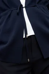 Ruana básica de tejido azul marino con cuello en V, cordón ajustable en la cintura y bolsillos frontales.