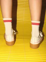 Championes bajos color crema con pespuntes rojos, capellada de tela canvas y plataforma de goma color caramelo de 4 cm de altura.