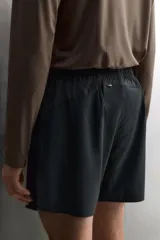 Short deportivo de entrenamiento en tejido técnico ligero y elástico, con cintura elástica ajustable mediante cordón. Presenta bolsillos frontales, un bolsillo trasero con cierre y aberturas laterales en el bajo. Incluye un pequeño logo estampado en la pernera.