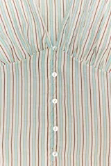 Camisa de manga larga con cuello redondo y escote en pico. Presenta un diseño a rayas verticales en tonos marrones y celestes, con detalle de pliegues en el delantero y los hombros. Cierre frontal con botones y puños ajustados.